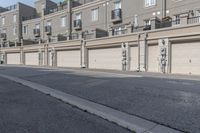 the building is stucco on the top floor and tall above the garage doors and the street is paved with gravel