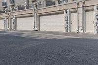 the building is stucco on the top floor and tall above the garage doors and the street is paved with gravel