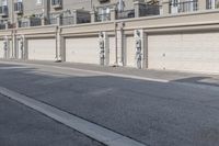 the building is stucco on the top floor and tall above the garage doors and the street is paved with gravel