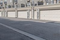 the building is stucco on the top floor and tall above the garage doors and the street is paved with gravel