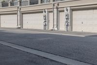 the building is stucco on the top floor and tall above the garage doors and the street is paved with gravel