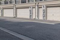 the building is stucco on the top floor and tall above the garage doors and the street is paved with gravel