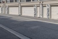 the building is stucco on the top floor and tall above the garage doors and the street is paved with gravel