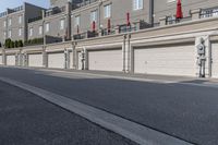 the building is stucco on the top floor and tall above the garage doors and the street is paved with gravel