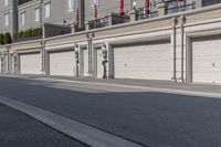 the building is stucco on the top floor and tall above the garage doors and the street is paved with gravel