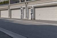 the building is stucco on the top floor and tall above the garage doors and the street is paved with gravel