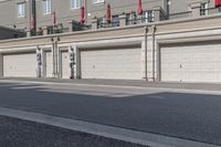 the building is stucco on the top floor and tall above the garage doors and the street is paved with gravel