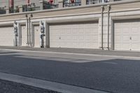 the building is stucco on the top floor and tall above the garage doors and the street is paved with gravel