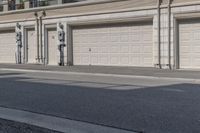 the building is stucco on the top floor and tall above the garage doors and the street is paved with gravel