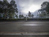 a view of the sun coming through clouds over a park, which is near by trees