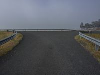 a road with a guard rail is in the middle of nowhere as fog comes in