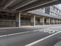 the empty street is near the big building at the intersection of the road and the side of a road