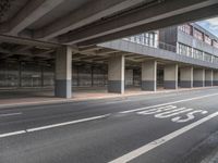 the empty street is near the big building at the intersection of the road and the side of a road