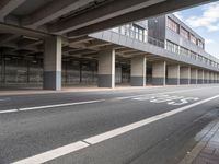 the empty street is near the big building at the intersection of the road and the side of a road