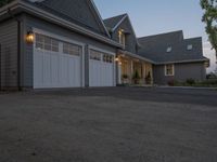 a grey three - car garage with the lights on next to it's entrance