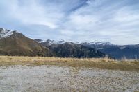 a group of people on a grassy field in front of mountains with snow capped tops