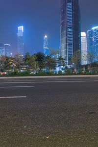 a city street with buildings and neon lights at night time in hong china as seen from an empty city highway