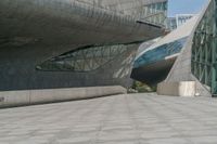 a long walkway leads to a very modern building that features various kinds of windows and doors