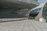 a long walkway leads to a very modern building that features various kinds of windows and doors