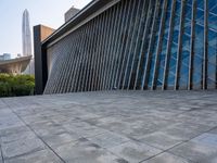 a square stone walkway leading to some very modern buildings with a sky line in the background