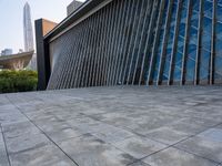 a square stone walkway leading to some very modern buildings with a sky line in the background