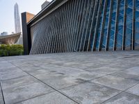 a square stone walkway leading to some very modern buildings with a sky line in the background