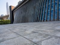 a square stone walkway leading to some very modern buildings with a sky line in the background