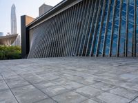 a square stone walkway leading to some very modern buildings with a sky line in the background