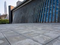 a square stone walkway leading to some very modern buildings with a sky line in the background