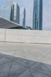 an empty area with concrete walls and some skyscrapers in the distance with a man standing on one side holding a backpack