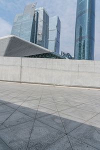 an empty area with concrete walls and some skyscrapers in the distance with a man standing on one side holding a backpack