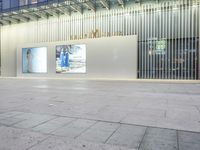 a person on a skateboard stands near a white wall with posters in front of a building