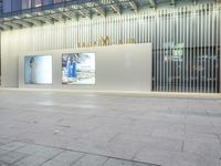 a person on a skateboard stands near a white wall with posters in front of a building