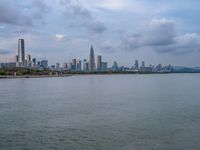 the water has very large chunks of blue in it and a skyline of large buildings in the background