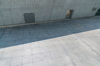 there is a long shadow on the pavement beside a wall and a parking lot with doors