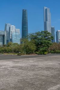 an empty parking lot in front of a skyline with high rise skyscrapers and green trees