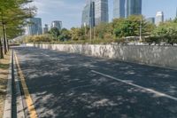 a quiet road in an area with high buildings in the background and many trees growing