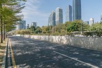 a quiet road in an area with high buildings in the background and many trees growing