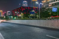 a city street with buildings and neon lights at night time in hong china as seen from an empty city highway