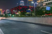 a city street with buildings and neon lights at night time in hong china as seen from an empty city highway