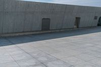 an empty skateboarder rides down the sidewalk on a sunny day in front of a building