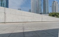 skate boarders are riding on a concrete pavement with tall buildings behind them as the person walks by