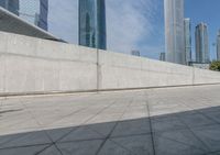 skate boarders are riding on a concrete pavement with tall buildings behind them as the person walks by