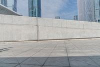 skate boarders are riding on a concrete pavement with tall buildings behind them as the person walks by