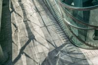 shadow on the ground next to a building with a metal railing and a man walking down it