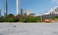 the skateboarder is on the concrete surface in front of tall buildings and trees