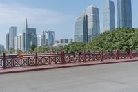 a person is walking across a bridge in the city center of a city there are trees and tall buildings