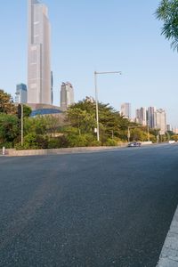 a person walking down the street towards an empty city with lots of buildings and trees in the background