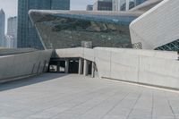 the man stands on the stairs in front of a large building that looks like a whale