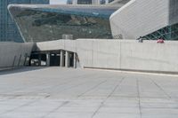 the man stands on the stairs in front of a large building that looks like a whale